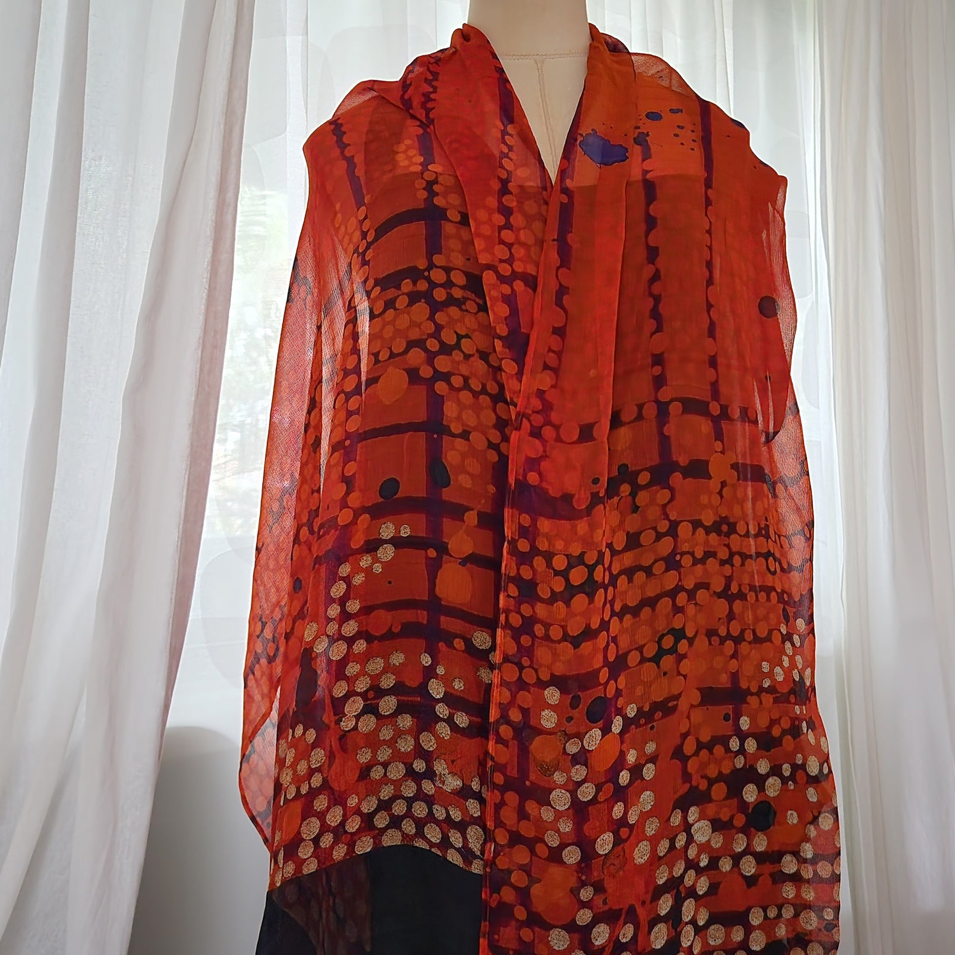 A silk chiffon scarf with a pattern in shades of red, black and white.