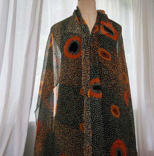 A silk chiffon scarf with a geometric pattern in shades of orange, green  and black.