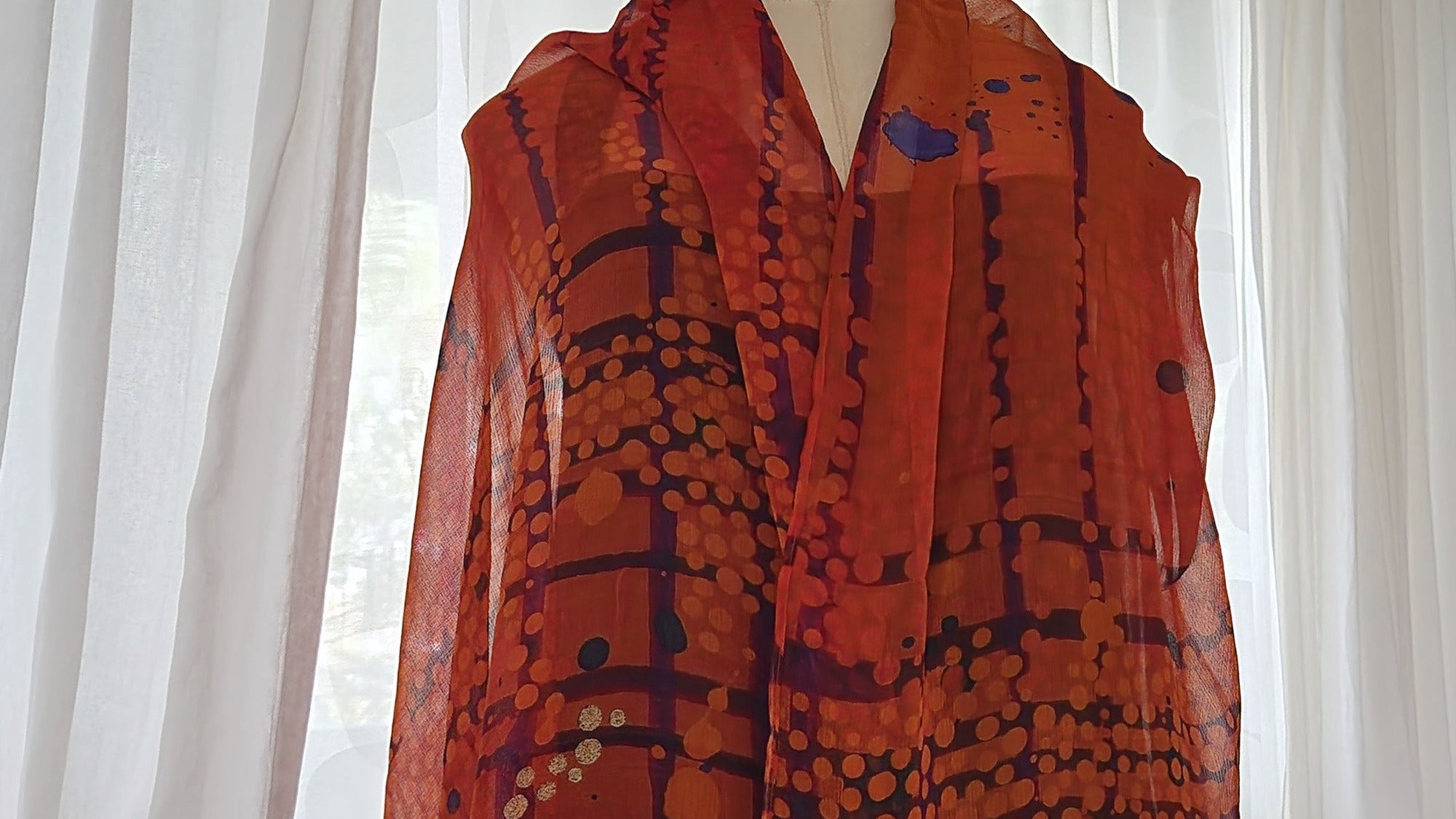 A silk chiffon scarf with a pattern in shades of red, black and white.