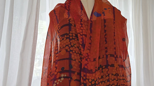 A silk chiffon scarf with a pattern in shades of red, black and white.